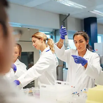 Three young scientists are seen working on a number of vials in the lab